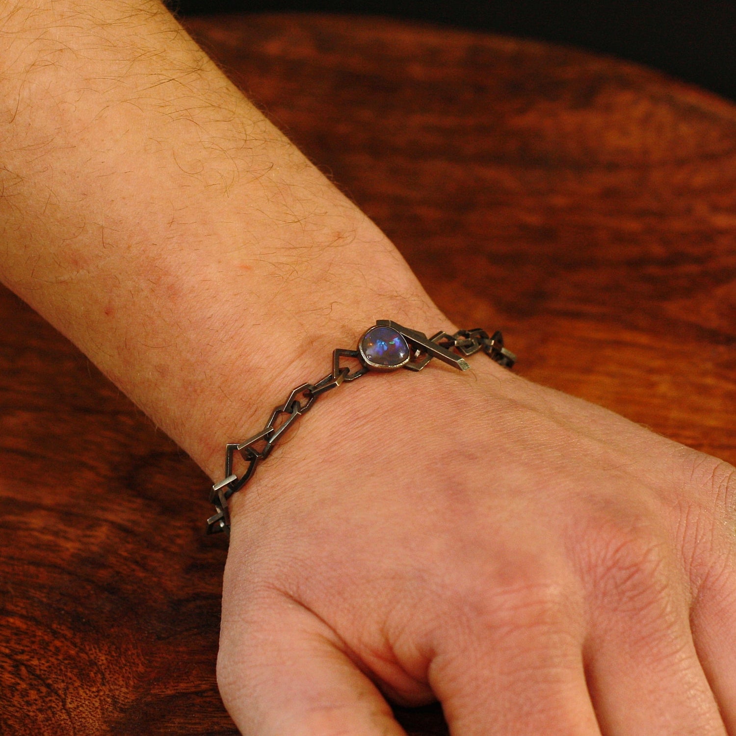 Markantes Herrenarmband aus dunklem Silber mit Opalverschluss an einem Handgelenk getragen