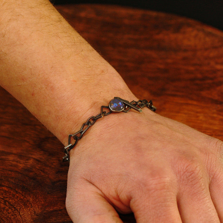 Markantes Herrenarmband aus dunklem Silber mit Opalverschluss an einem Handgelenk getragen