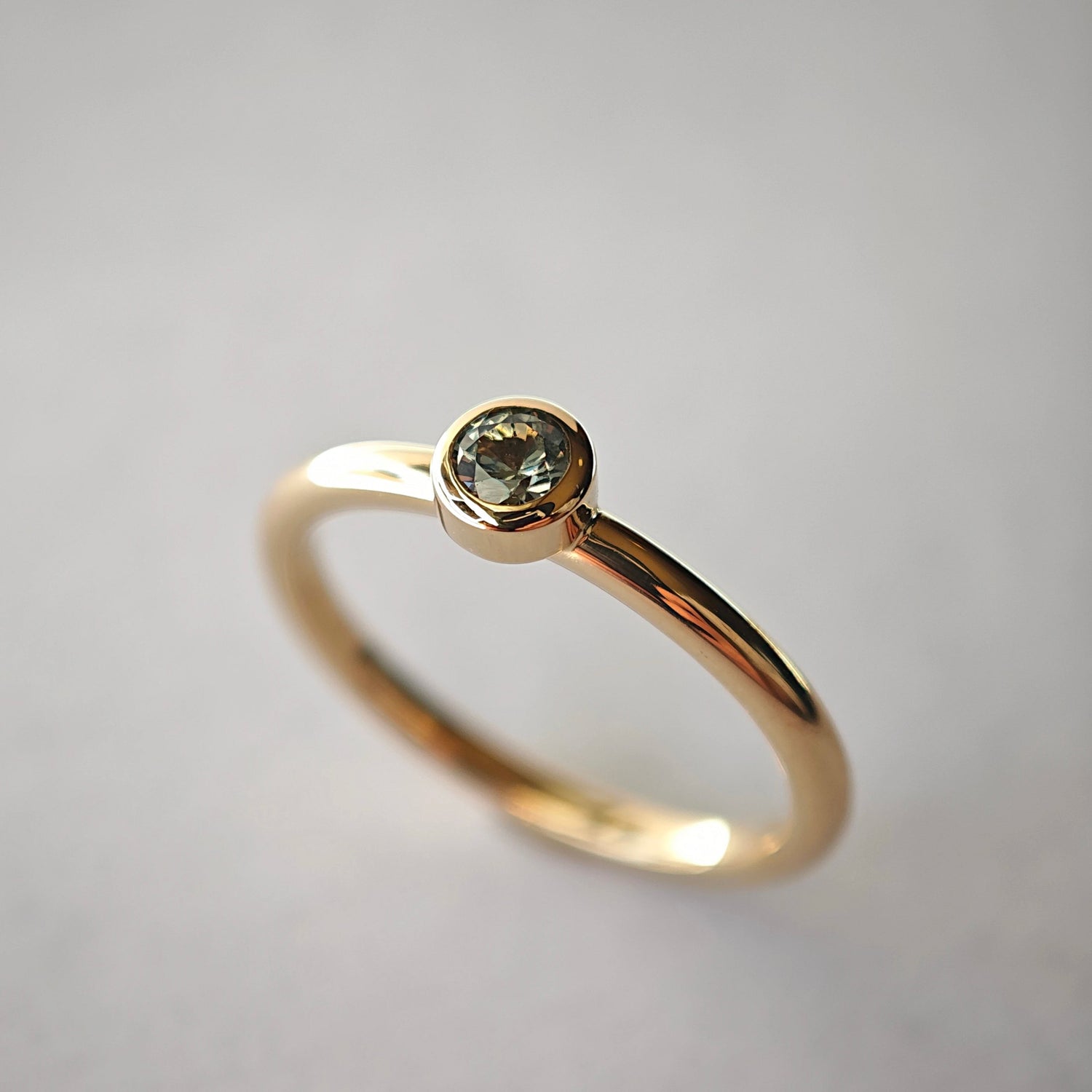 Verlobungsring aus Gold mit einem gefassten Solitär-Edelstein vor hellem Hintergrund