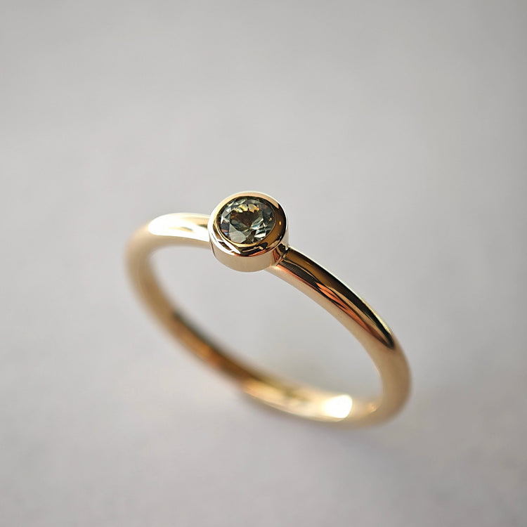 Verlobungsring aus Gold mit einem gefassten Solitär-Edelstein vor hellem Hintergrund