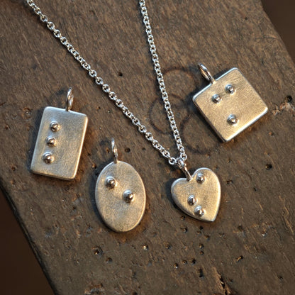 Silberschmuck mit Brailleschrift, Blindenschrift als ID Kettenanhänger, vier handgefertigte Anhänger auf dem Feilnagel der Goldschmiedemeisterin