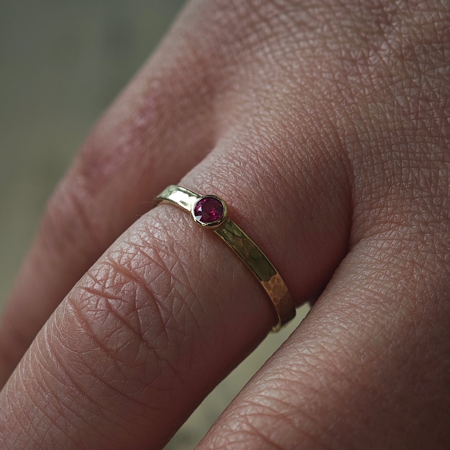 Ring am Finger getragen: Goldring mit Rubin und Hammerschlag