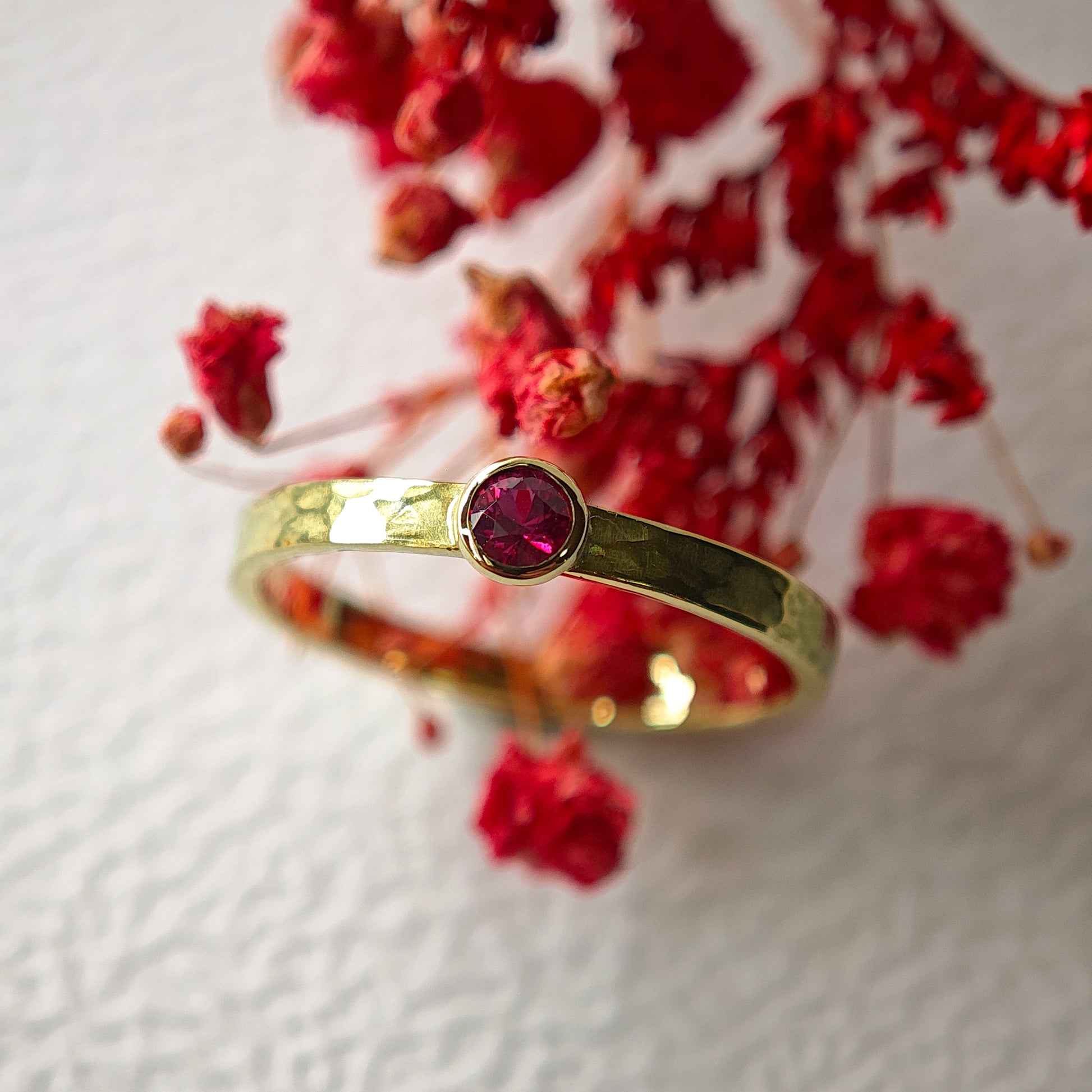 Goldring mit pinkem Rubin in roten Blüten