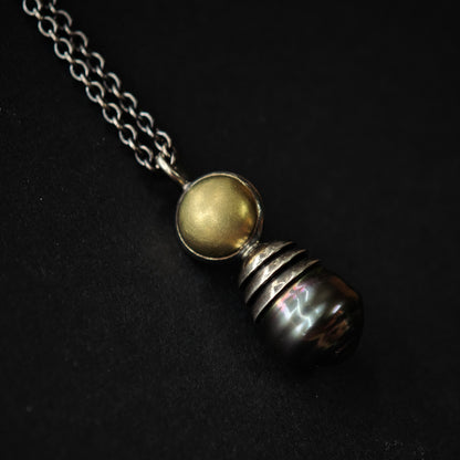 Nahaufnahme von Kettenanhänger auf dunklem Untergrund: Tahiti-Perle in oxidiertem Silber und Gold